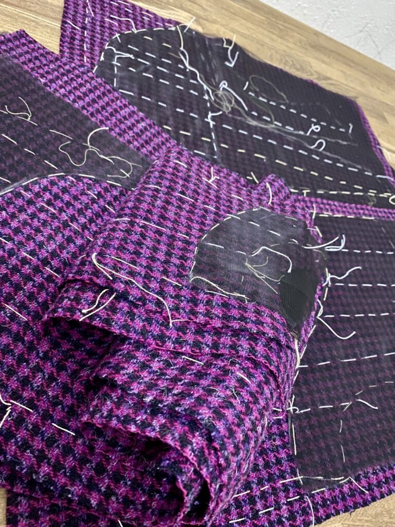 Construction intérieure d’une veste en Harris Tweed avec organza de soie fixée par matelassage à la main afin de préserver la souplesse naturelle du tissu.